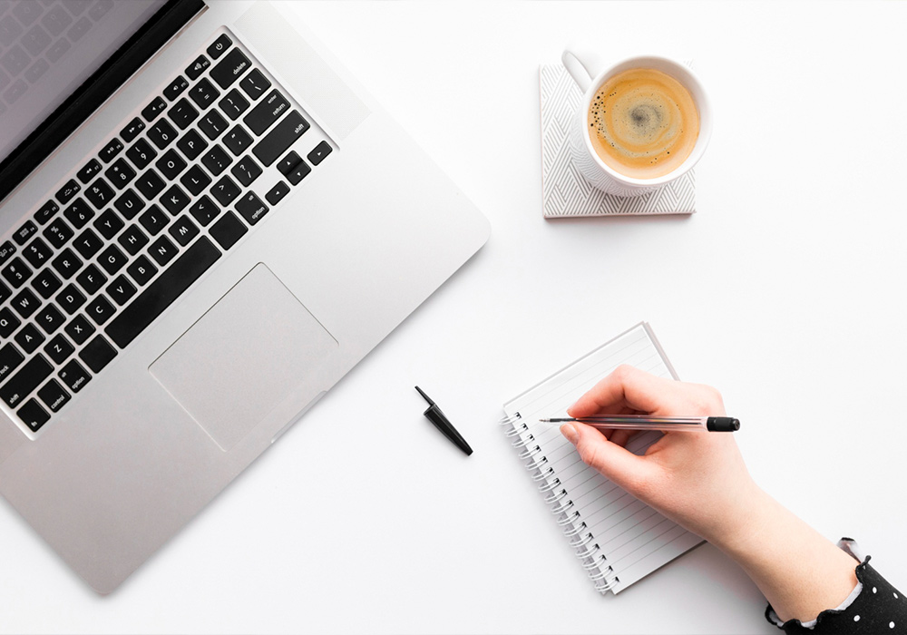 writing blogs about your niche taking notes from laptop
